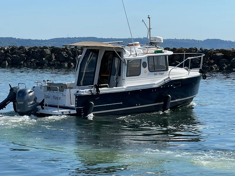 Slide: The Image of 2018 Ranger Tugs R23 boat cruising on calm water near rocky shoreline. - 9