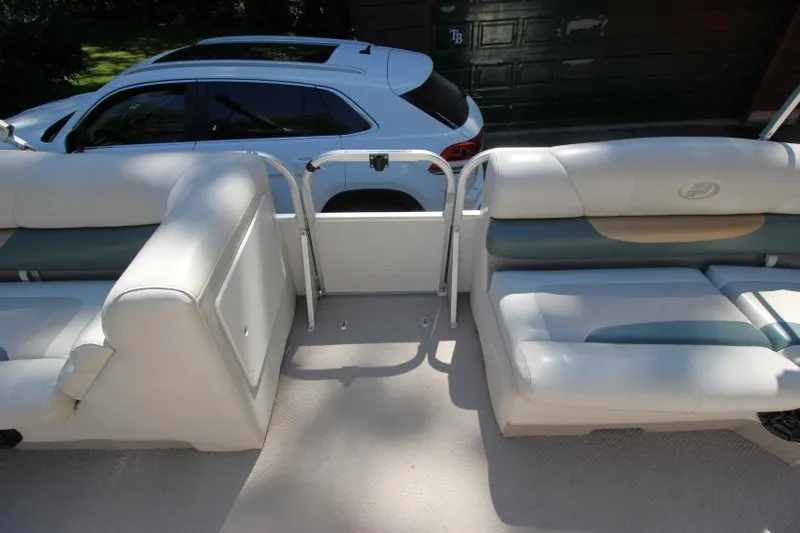 Slide: The Image of 2002 Princecraft Versailles 22 SS boat interior with white seating, parked near a white car. - 13