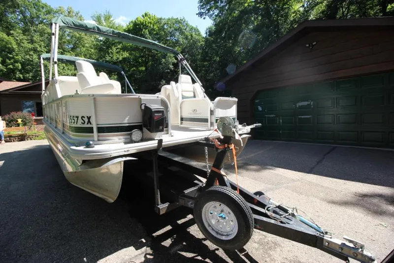 Slide: The Image of 2002 Princecraft Versailles 22 SS pontoon boat on trailer, parked near a garage. - 2