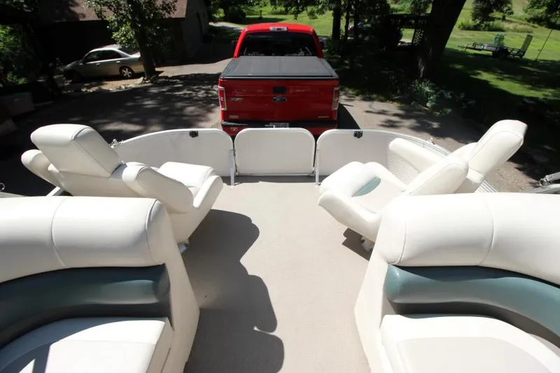 Slide: The Image of 2002 Princecraft Versailles 22 SS pontoon boat interior with white seating, parked near a red truck. - 9