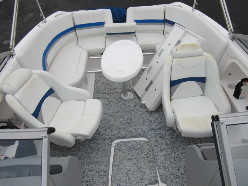 Slide: The Image of 2004 Yamaha Boats SX230 interior with white and blue seating, round table, and carpeted floor. - 18