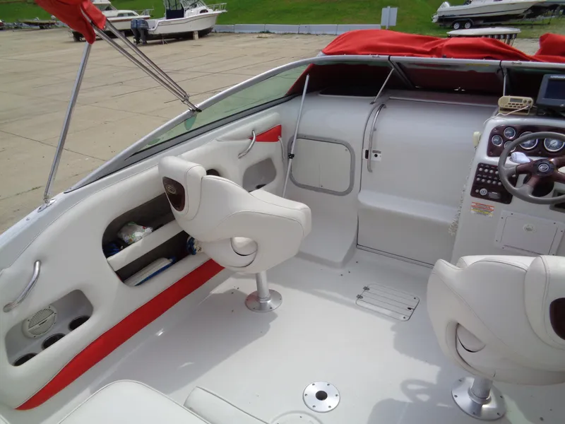 Slide: The Image of 2006 Crownline 220 CCR boat interior with white seating and red accents, docked at marina. - 14