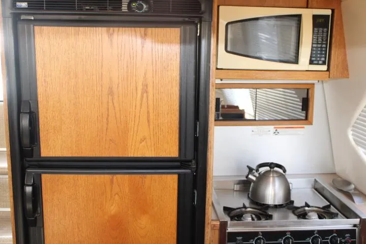 Slide: The Image of 1997 Bayliner 4087 yacht kitchen with fridge, microwave, stove, and kettle. - 31