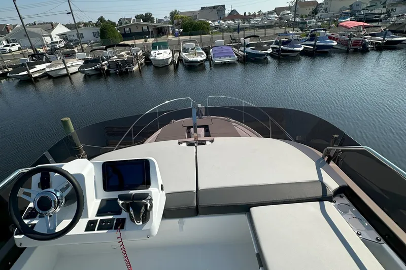 Slide: The Image of Flybridge view of 2022 Jeanneau NC 1095 Fly, overlooking marina with multiple boats docked. - 6