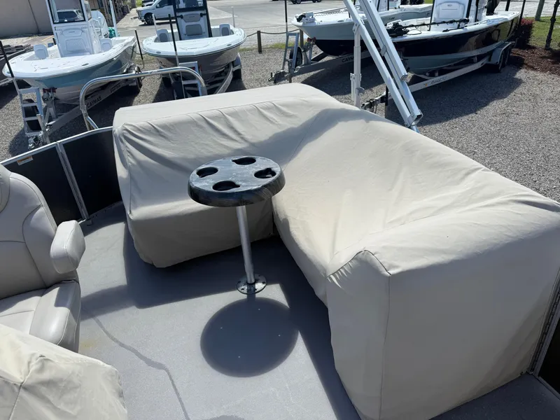 Slide: The Image of 2017 Sweetwater 2286 C boat interior with covered seating and table, parked near other boats. - 11