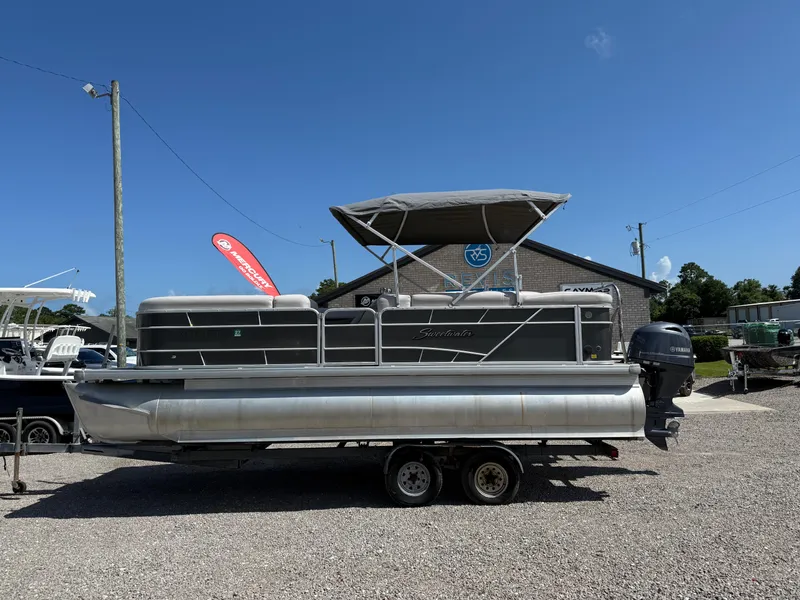 Slide: The Image of 2017 Sweetwater 2286 C pontoon boat on trailer, parked outdoors under clear blue sky. - 15