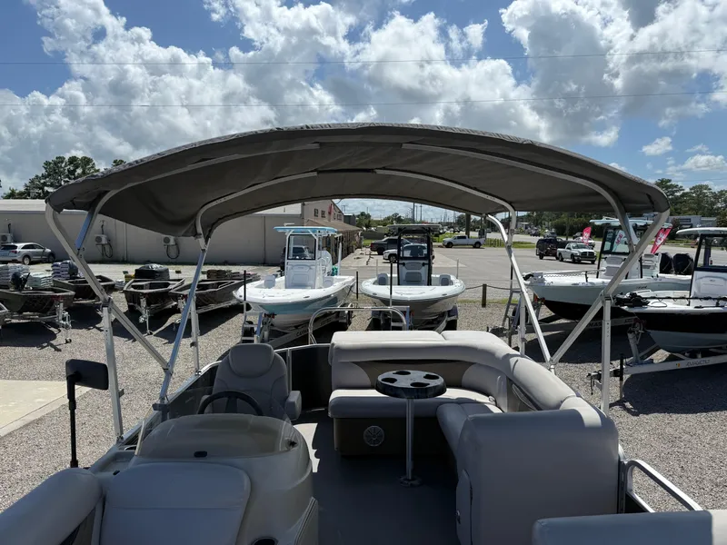 Slide: The Image of 2017 Sweetwater 2286 C pontoon boat with canopy, parked among other boats under a cloudy sky. - 16