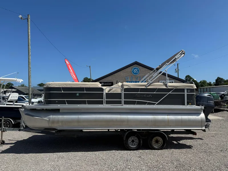 Slide: The Image of 2017 Sweetwater 2286 C pontoon boat on trailer, parked outdoors under clear blue sky. - 2