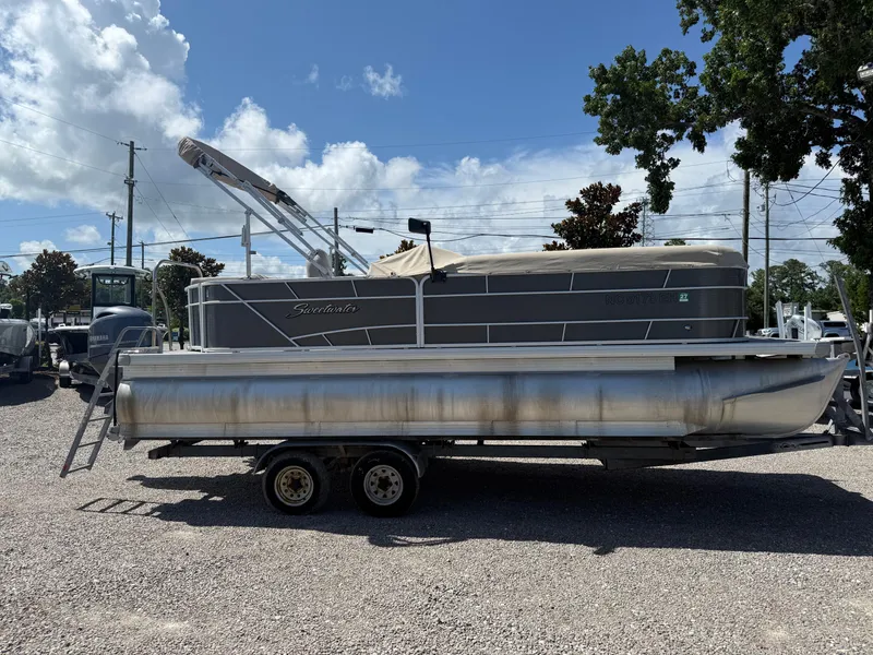 Slide: The Image of 2017 Sweetwater 2286 C pontoon boat on trailer, parked outdoors under a sunny sky. - 6