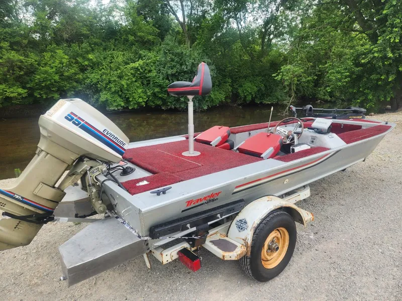 Slide: The Image of 1987 Sea Nymph Traveler boat with Evinrude motor on a trailer by a riverbank. - 3