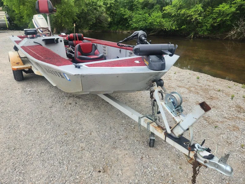 Slide: The Image of 1987 Sea Nymph Traveler boat on trailer by a riverbank, featuring red interior. - 6