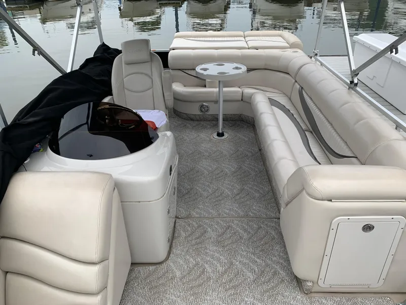 Slide: The Image of Interior of a 2009 South Bay 825 CR pontoon boat with beige seating and table. - 2