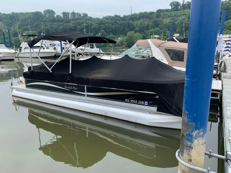Slide: The Image of 2009 South Bay 825 CR pontoon boat docked with black cover, surrounded by other boats. - 9