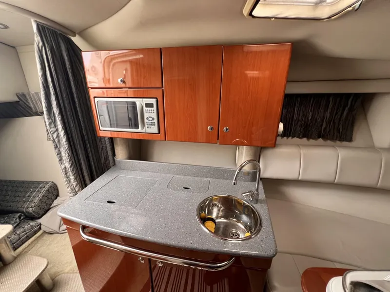 Slide: The Image of 2006 Formula 27 PC boat interior with kitchenette, featuring microwave, sink, and wooden cabinets. - 30