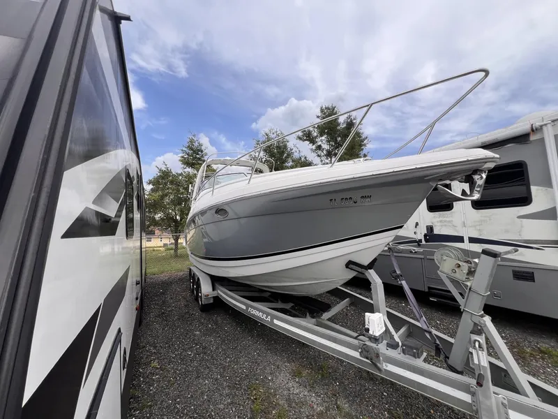 Slide: The Image of 2006 Formula 27 PC boat on trailer, parked between RVs under cloudy sky. - 9