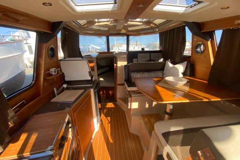 Slide: The Image of 2016 Ranger Tugs R-29S interior with wood finishes, dining area, and natural light. - 15