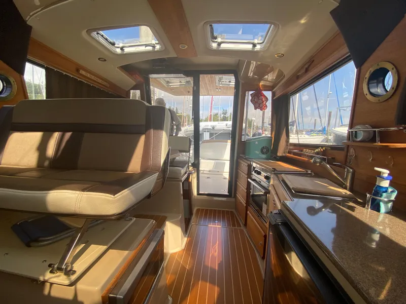 Slide: The Image of Interior of 2016 Ranger Tugs R-29S boat with seating, kitchen, and sunlight through windows. - 19