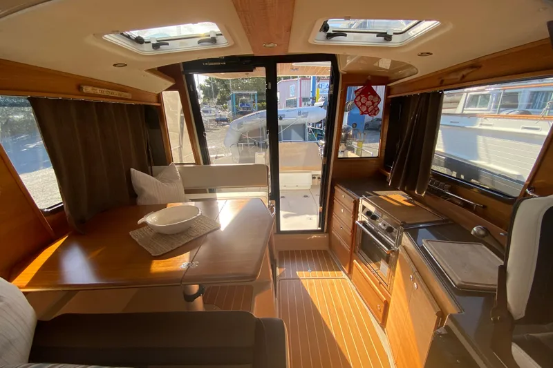 Slide: The Image of Interior of 2016 Ranger Tugs R-29S, featuring dining area and kitchen with wood accents. - 20