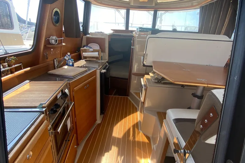 Slide: The Image of Interior of 2016 Ranger Tugs R-29S, featuring a compact kitchen and dining area. - 23