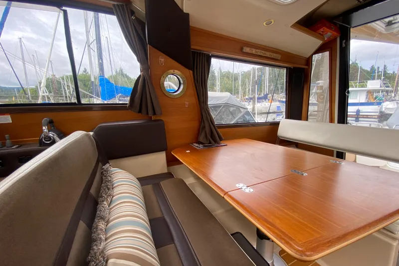 Slide: The Image of Interior of 2016 Ranger Tugs R-29S with wooden table and seating, marina view. - 24