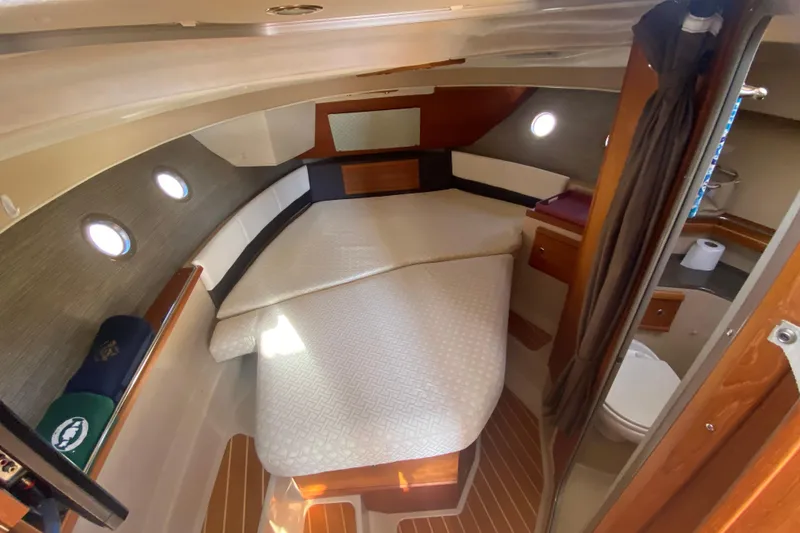 Slide: The Image of 2016 Ranger Tugs R-29S cabin interior with bed, portholes, and wooden accents. - 32