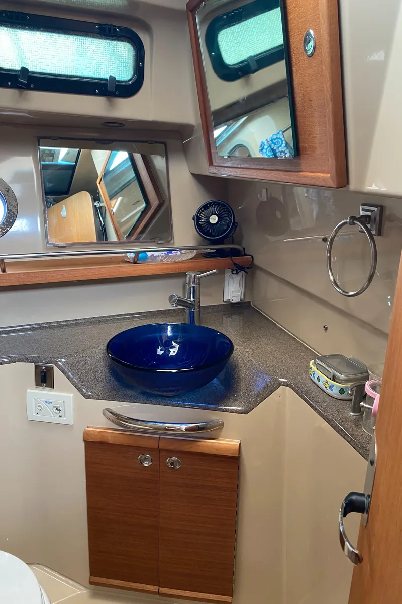 Slide: The Image of 2016 Ranger Tugs R-29S bathroom with blue vessel sink and wooden cabinetry. - 33