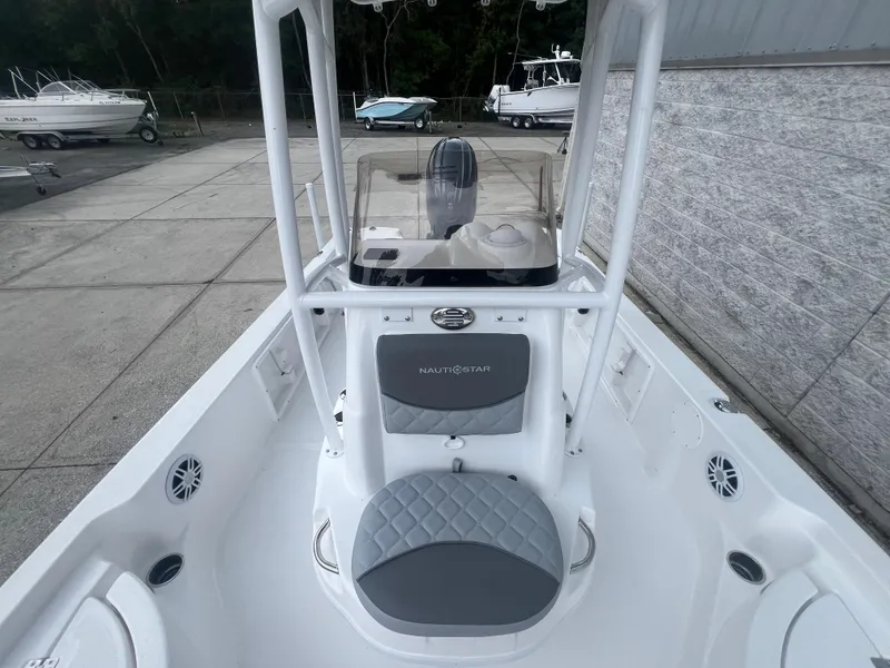 Slide: The Image of 2025 NauticStar 214 Shallow Bay boat interior with seating and console, docked outdoors. - 20