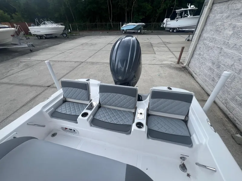 Slide: The Image of 2025 NauticStar 214 Shallow Bay boat with gray seating and outboard motor in a marina. - 6