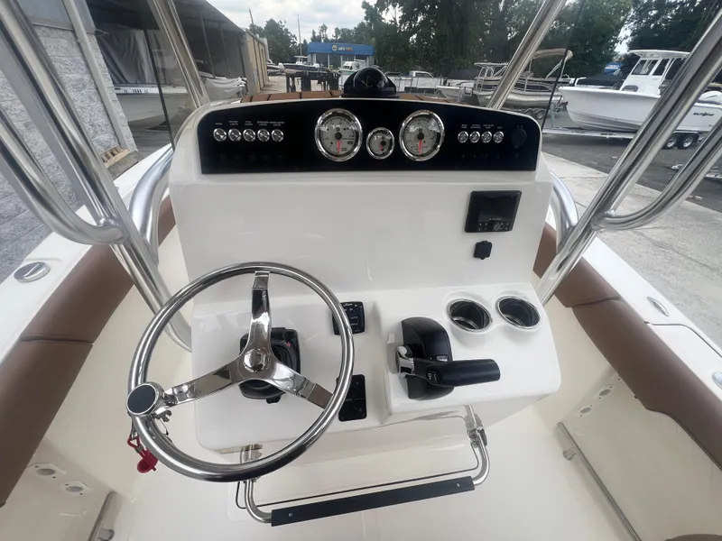 Slide: The Image of 2026 Pioneer 202 Islander boat console with steering wheel, gauges, and controls in a marina setting. - 16