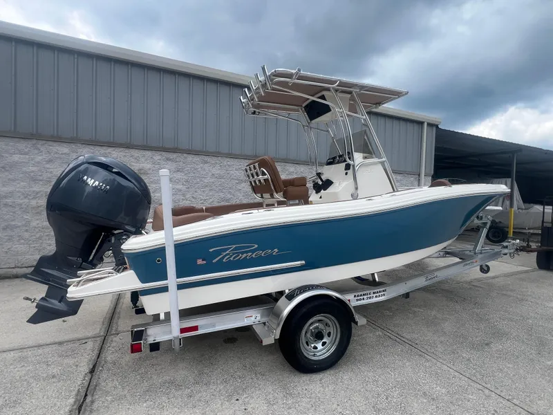 Slide: The Image of 2026 Pioneer 202 Islander boat on trailer, blue hull, Yamaha outboard, parked outdoors. - 2