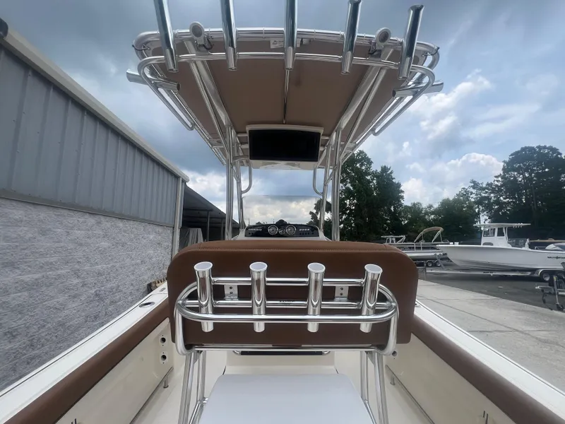 Slide: The Image of 2026 Pioneer 202 Islander boat interior with rod holders and canopy under cloudy sky. - 7