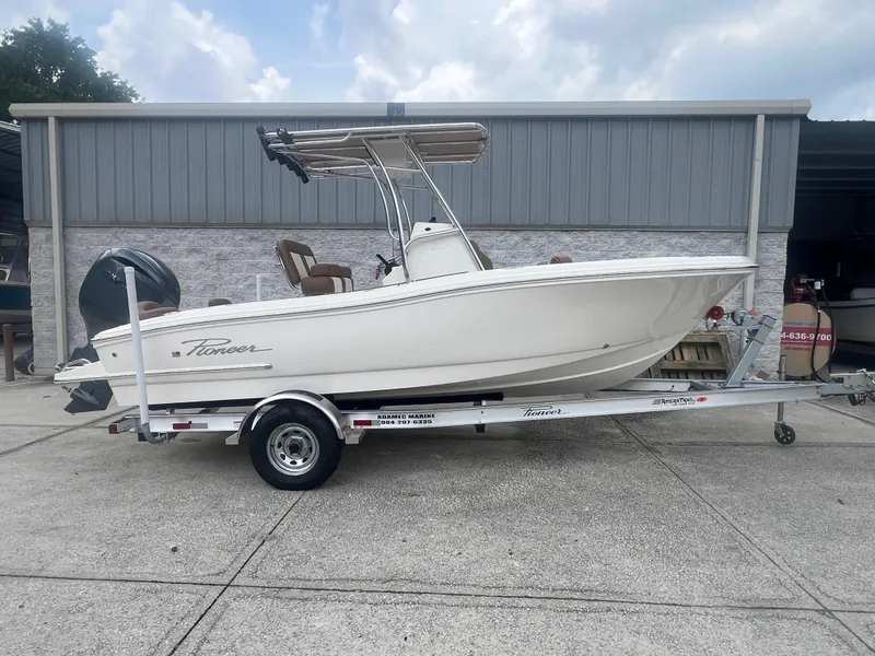 Slide: The Image of 2026 Pioneer 202 Islander boat on trailer, parked outside a metal building. - 2