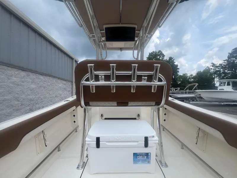Slide: The Image of 2026 Pioneer 202 Islander boat interior with Engel cooler and rod holders under cloudy sky. - 23
