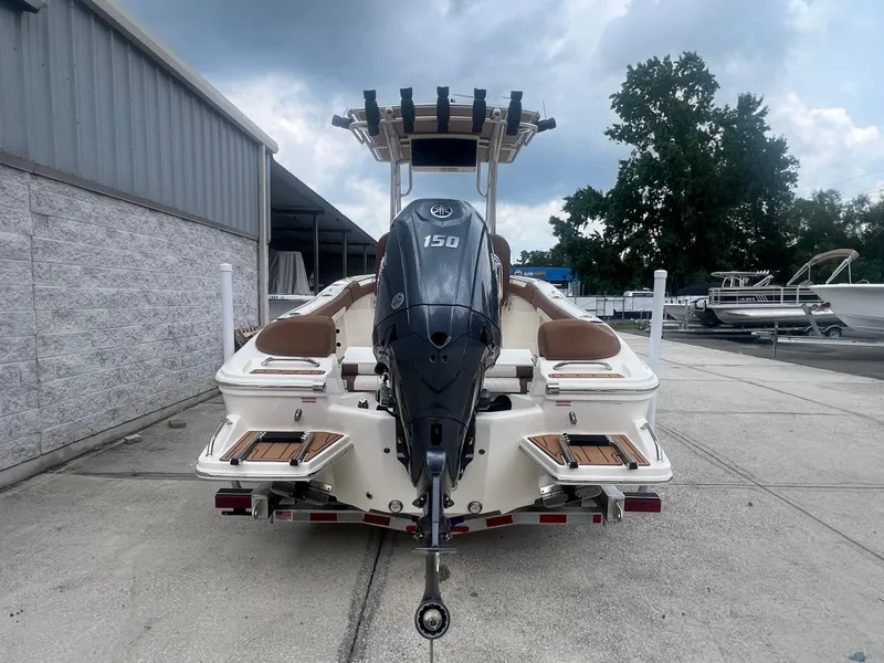 Slide: The Image of 2026 Pioneer 202 Islander boat with 150 HP engine, parked outdoors under cloudy sky. - 4