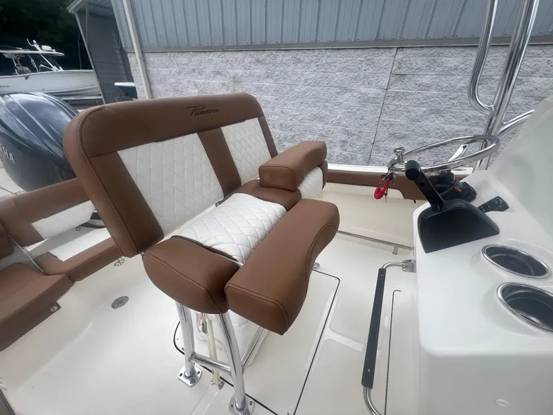 Slide: The Image of 2026 Pioneer 202 Islander boat interior with brown and white seating, steering console, and cup holders. - 8