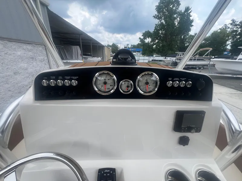 Slide: The Image of 2026 Pioneer 202 Islander boat dashboard with gauges and controls, under a cloudy sky. - 9
