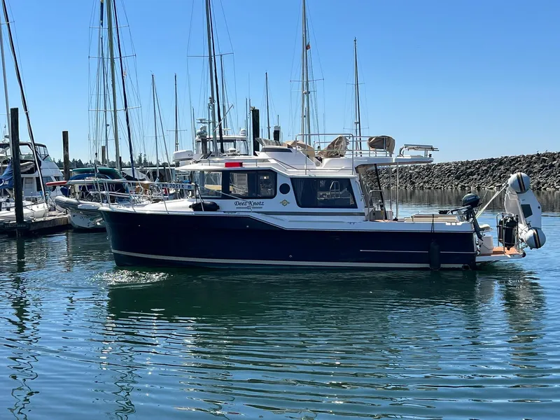 Slide: The Image of 2025 Ranger Tugs R-29 CB boat docked in a marina under clear blue skies. - 14