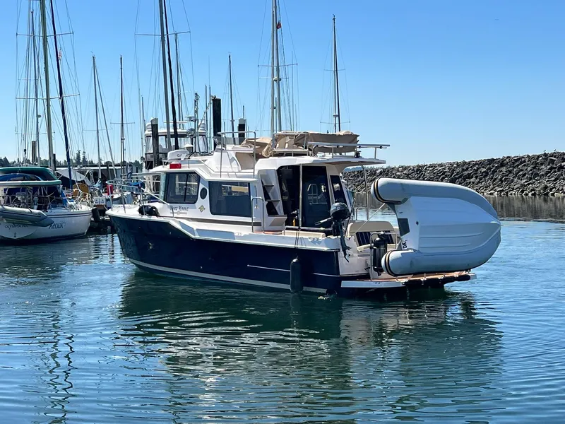 Slide: The Image of 2025 Ranger Tugs R-29 CB boat docked in a marina, clear blue sky. - 16