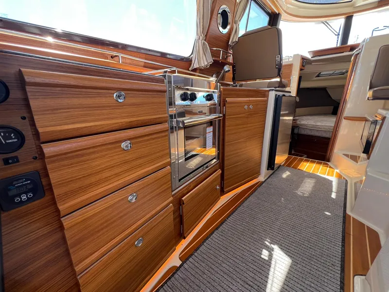Slide: The Image of Interior of 2025 Ranger Tugs R-29 CB, featuring wood cabinetry and modern appliances. - 23