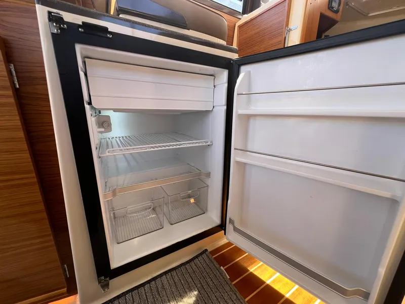 Slide: The Image of Open refrigerator inside 2025 Ranger Tugs R-29 CB boat, showcasing interior storage space. - 27