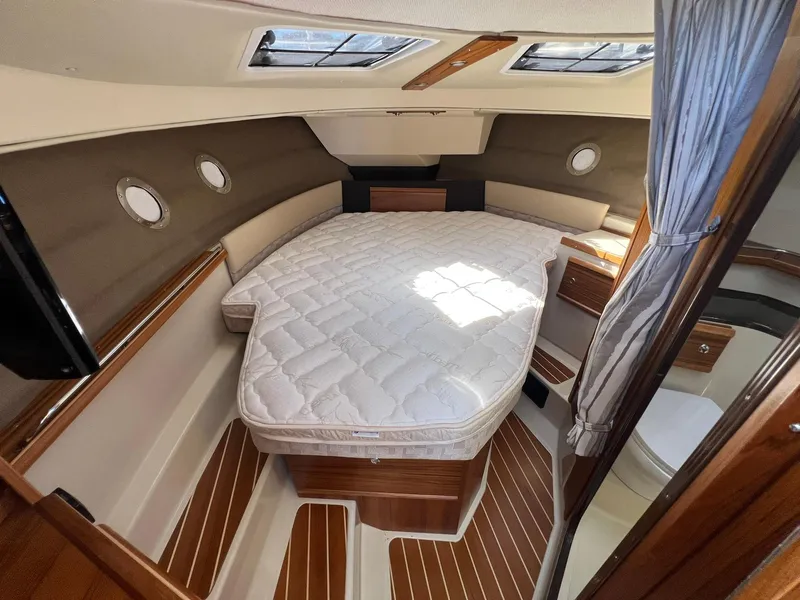 Slide: The Image of 2025 Ranger Tugs R-29 CB cabin interior with bed, wood accents, and portholes. - 28