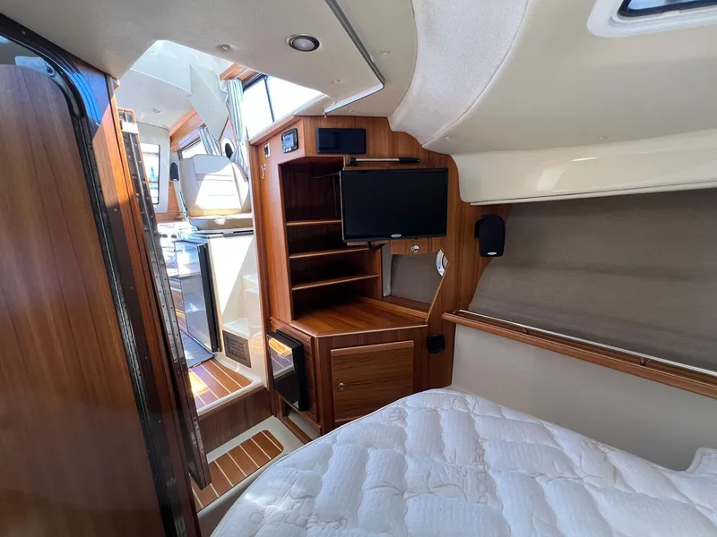 Slide: The Image of Interior of 2025 Ranger Tugs R-29 CB, featuring wood cabinetry, bed, and mounted TV. - 30
