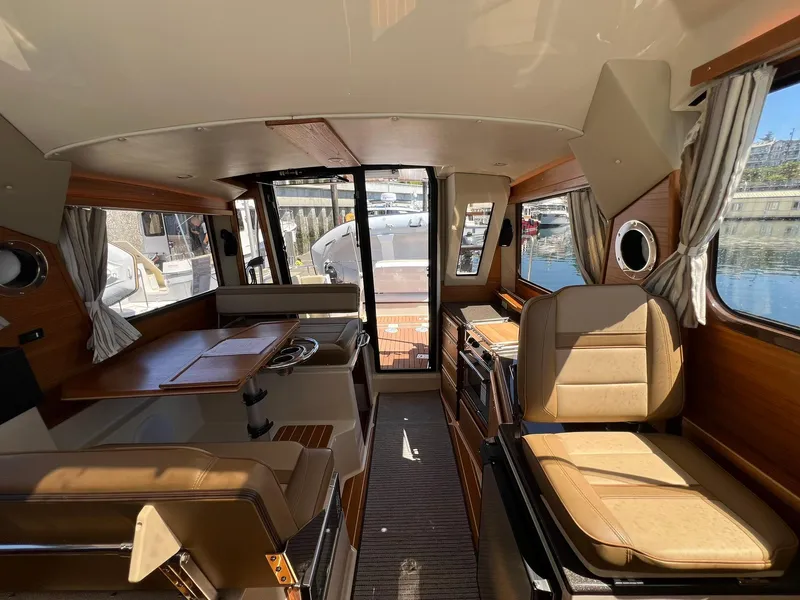 Slide: The Image of Interior of 2025 Ranger Tugs R-29 CB, featuring seating and dining area with wood accents. - 31