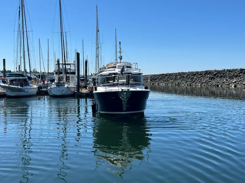 Slide: The Image of 2025 Ranger Tugs R-29 CB in marina, surrounded by sailboats, under clear blue sky. - 8