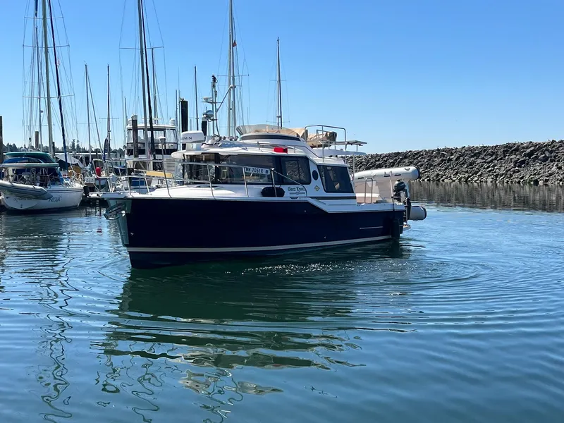 Slide: The Image of 2025 Ranger Tugs R-29 CB boat docked in a marina, surrounded by sailboats. - 9