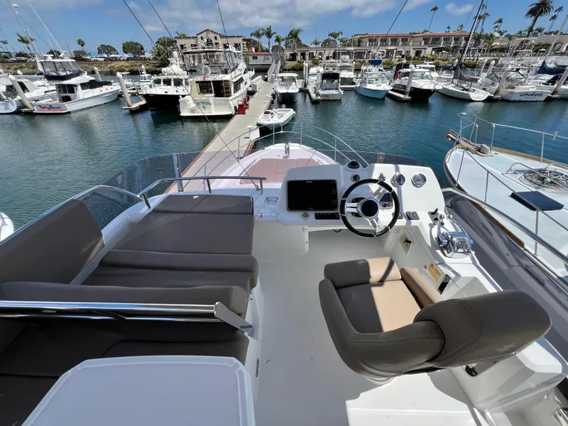Slide: The Image of Flybridge of 2017 Jeanneau Velasco 43 yacht docked in a marina, featuring helm and seating area. - 24