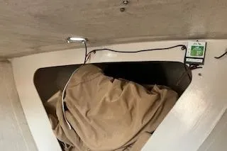 Slide: The Image of Interior view of a 1999 Alerion 26 sailboat with storage area and beige cover. - 17