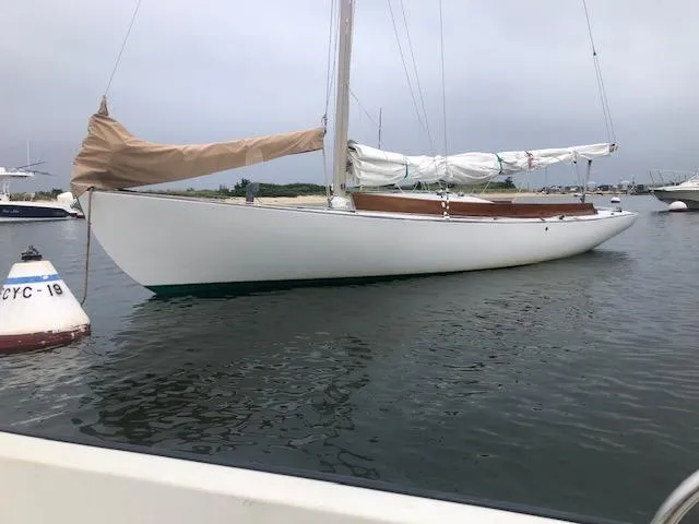 Slide: The Image of Alerion 26 sailboat from 1999 moored in calm waters, with sails covered. - 2
