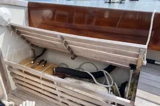 Slide: The Image of Storage compartment on a 1999 Alerion 26 sailboat, featuring wooden slats and nautical equipment. - 22