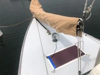 Slide: The Image of Alerion 26 sailboat deck, 1999 model, with beige sail cover and hatch, on calm water. - 7